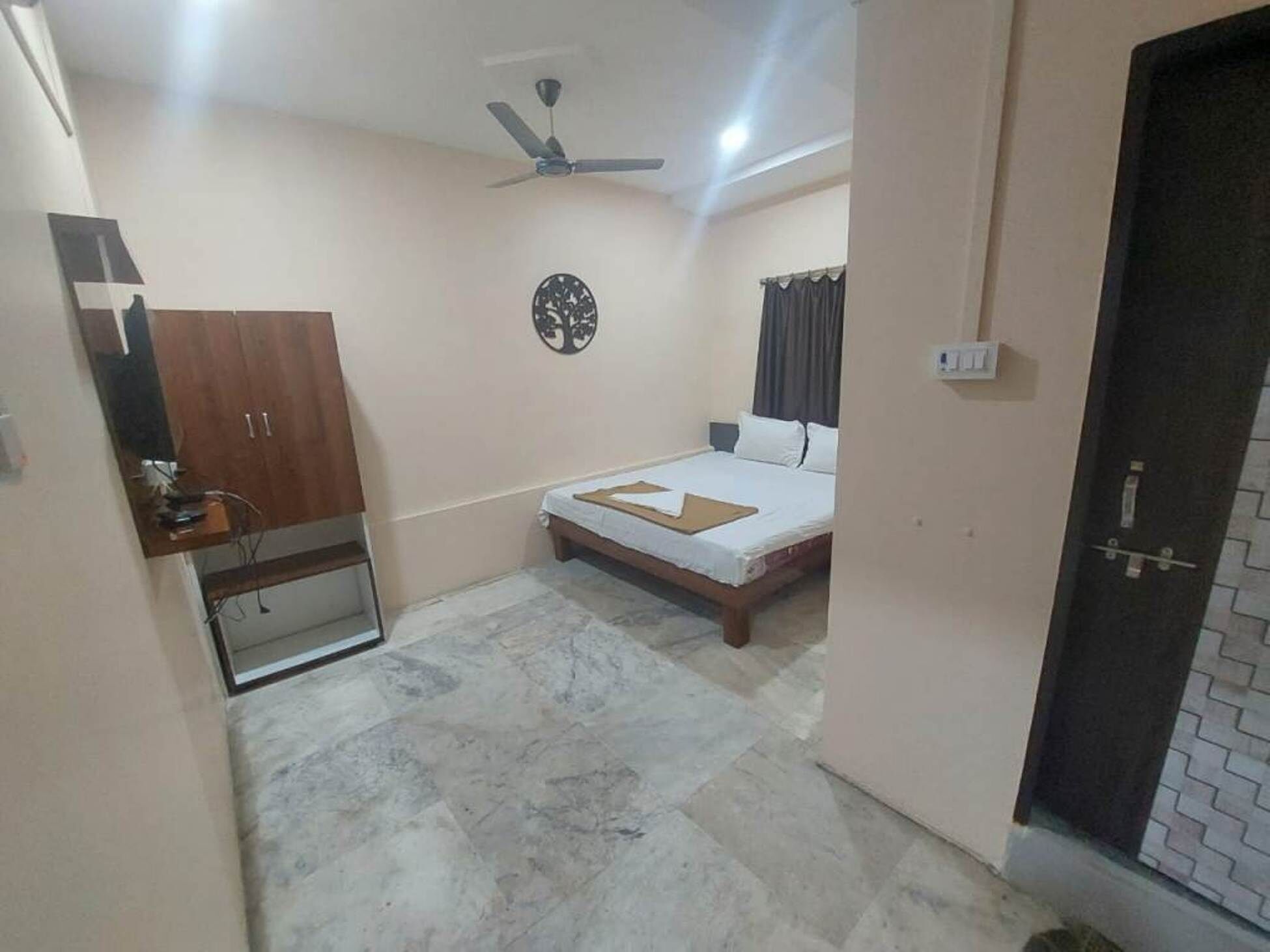 A bedroom with a bed, a ceiling fan, a wardrobe, and a mirror.