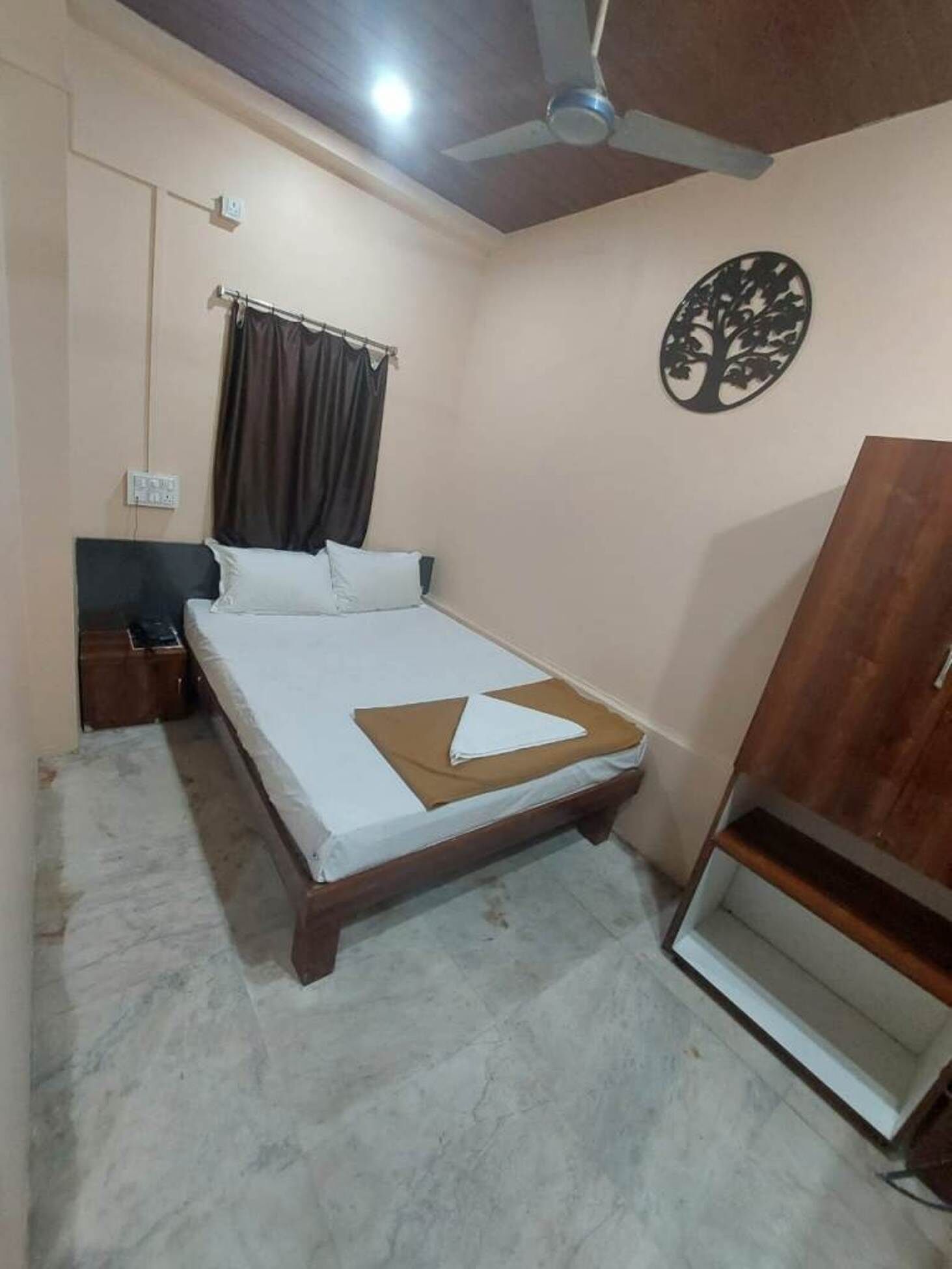 A bedroom with a bed, a ceiling fan, a nightstand, a wardrobe, and a wall decoration.
