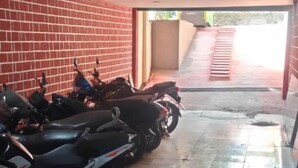 A covered parking area with tiled flooring and a brick wall. - iROOMZ City Lite Lodge (Nizamabad)