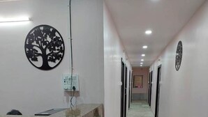 A reception area with a marble counter, a tree-shaped wall decoration, and a sign labeled "RECEPTION". - iROOMZ City Lite Lodge (Nizamabad)