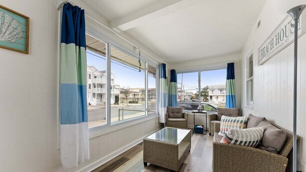 A room with a view of the sea, a wicker sofa, a glass coffee table, and a chair.