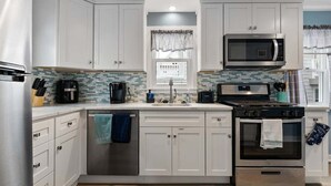 A kitchen with white cabinets, a microwave, a stove, and a dishwasher.