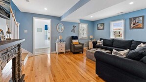 A living room with a stone fireplace, a dark sofa, a coffee table, and a blue wall.