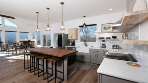 Una cucina moderna con un'isola in legno, elettrodomestici in acciaio inossidabile e illuminazione a sospensione.