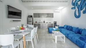 A modern living space with a dining area, kitchen, and a blue sofa. - Villa Rio (Canggu)