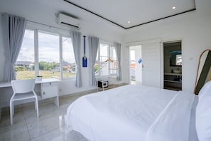 Relax in a spacious room with a large bed, desk, and wardrobe, offering a view of the surrounding area.