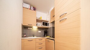 Una cocina compacta con armarios de madera, un microondas y una cafetera.