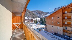 Un balcón de madera con vistas a un hotel y montañas nevadas.
