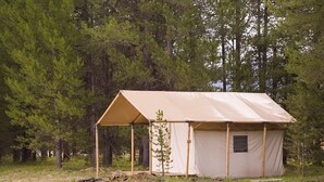 A single-room tent with a canvas roof and walls, surrounded by trees. - Yellowstone Luxury Safari Tent, sleeps 6 w/ 1 king (Island Park)