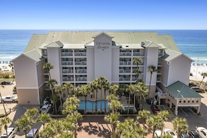 A hotel with a pool, multiple balconies, and a beach view.