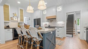 A modern kitchen with a central island, pendant lighting, and a herringbone-patterned backsplash.