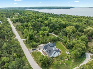 An aerial view of a residential area with a house surrounded by dense greenery and a lake in the background. - New luxury build w/ Hot tub - Immaculate Vita Huset in Sister Bay (Sister Bay)
