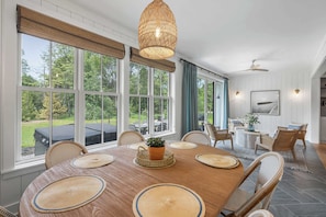 A spacious dining area with a large wooden table, woven placemats, wicker chairs, and a hanging light fixture. - New luxury build w/ Hot tub - Immaculate Vita Huset in Sister Bay (Sister Bay)