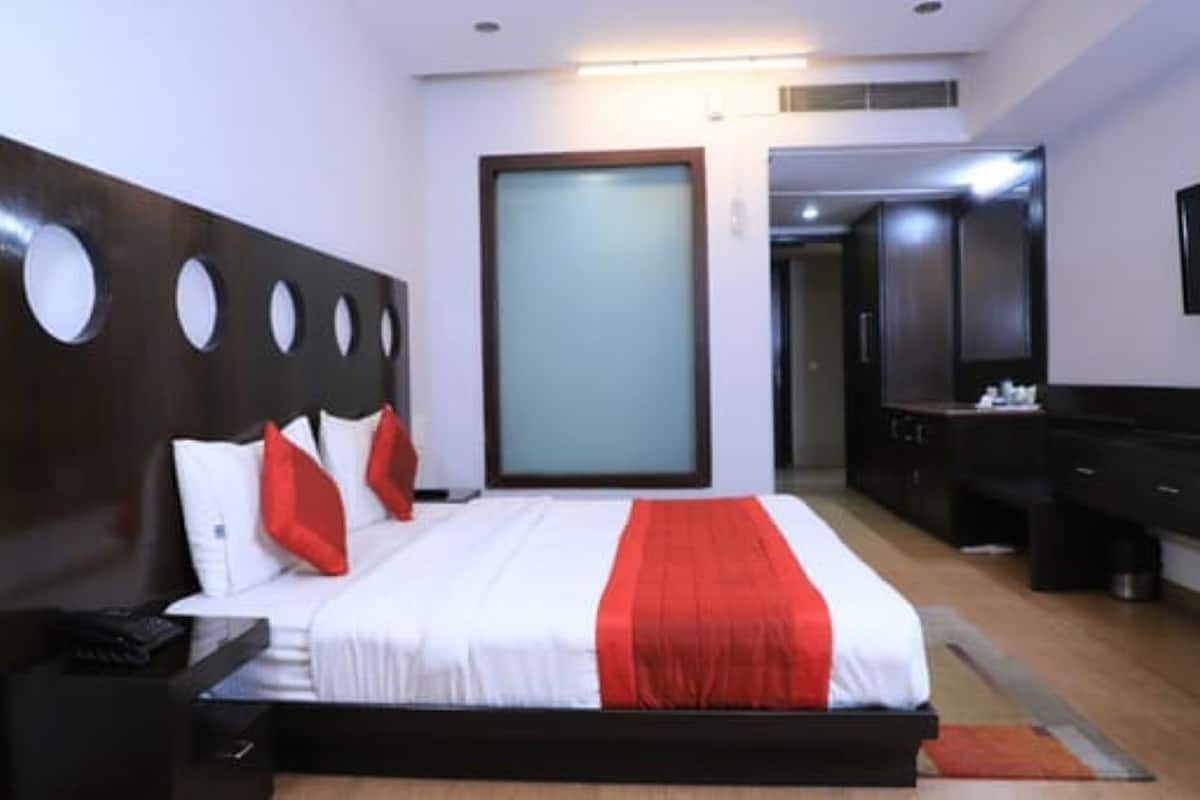 Una habitación de hotel con cama, mesita de noche, cómoda y espejo.