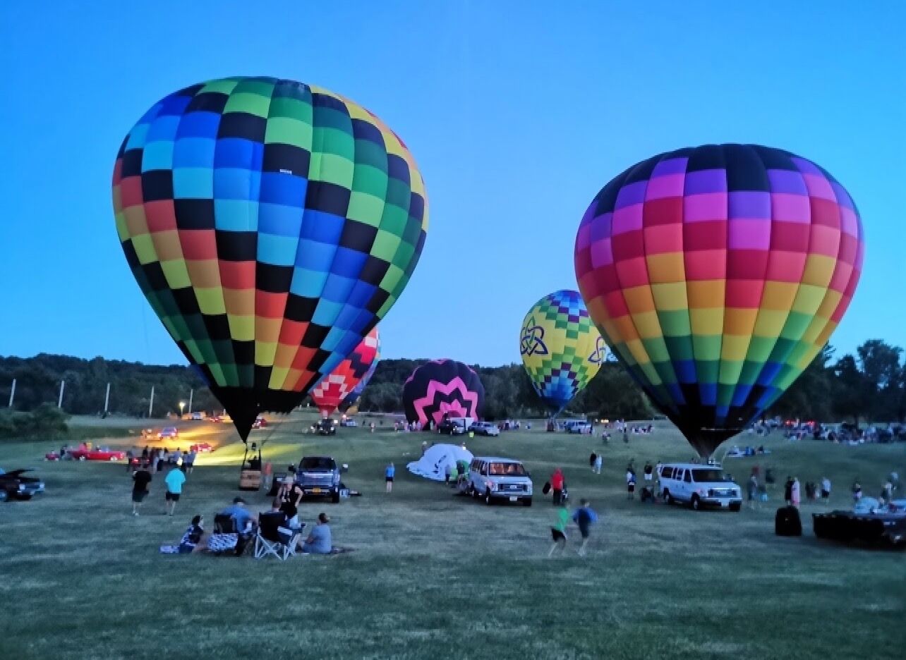 A field with several hot air balloons, some with checkered patterns and one with a star design.
