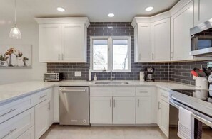 Enjoy cooking in this well-equipped kitchen with an oven, dishwasher, and sink under a window.