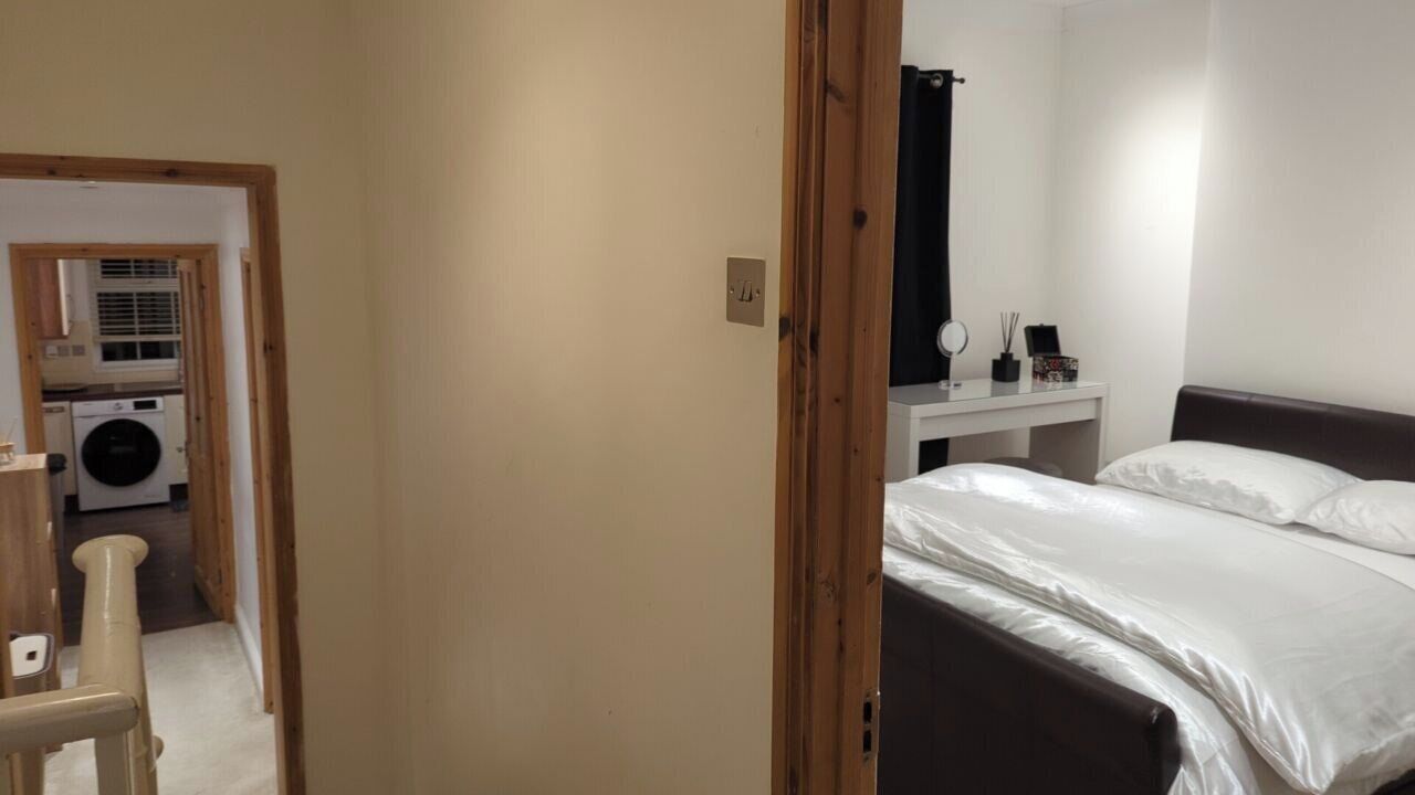 Una camera da letto con un letto, un comodino, uno specchio e vista sul bagno.