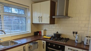 Een praktische keuken met een gasfornuis, oven en een klein spoelbakje.
