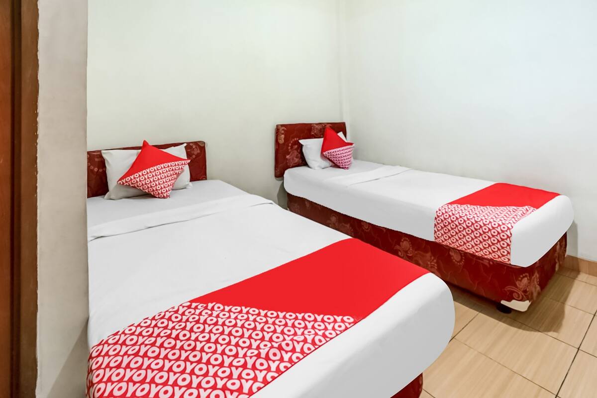 Habitación con dos camas, cada una con ropa de cama y almohadas a cuadros rojo y blanco.