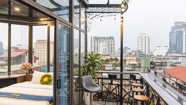 Un balcón con cama, zona de comedor y vistas a la ciudad.