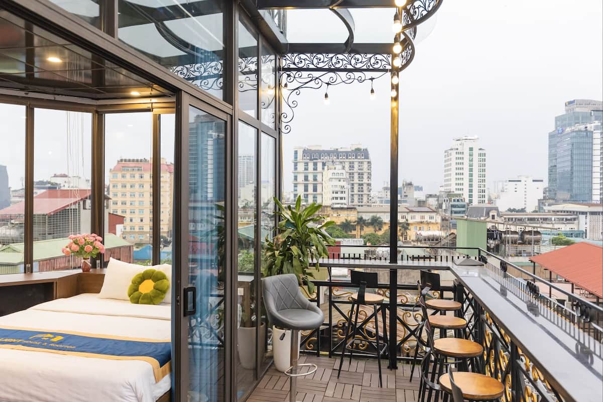 A balcony with a bed, a dining area, and a city view.