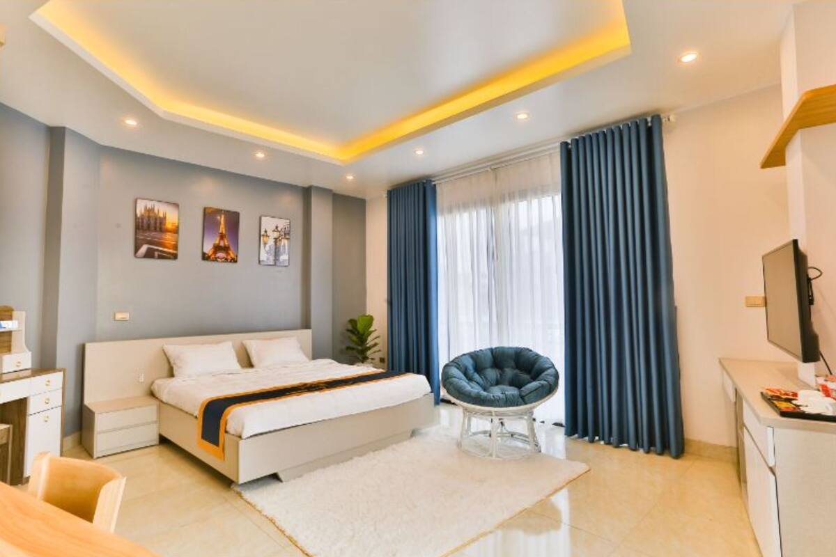 A modern hotel room with a bed, a desk, a chair, and a TV.