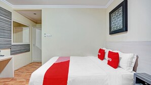 A hotel room with a bed, a desk, and a mirror.