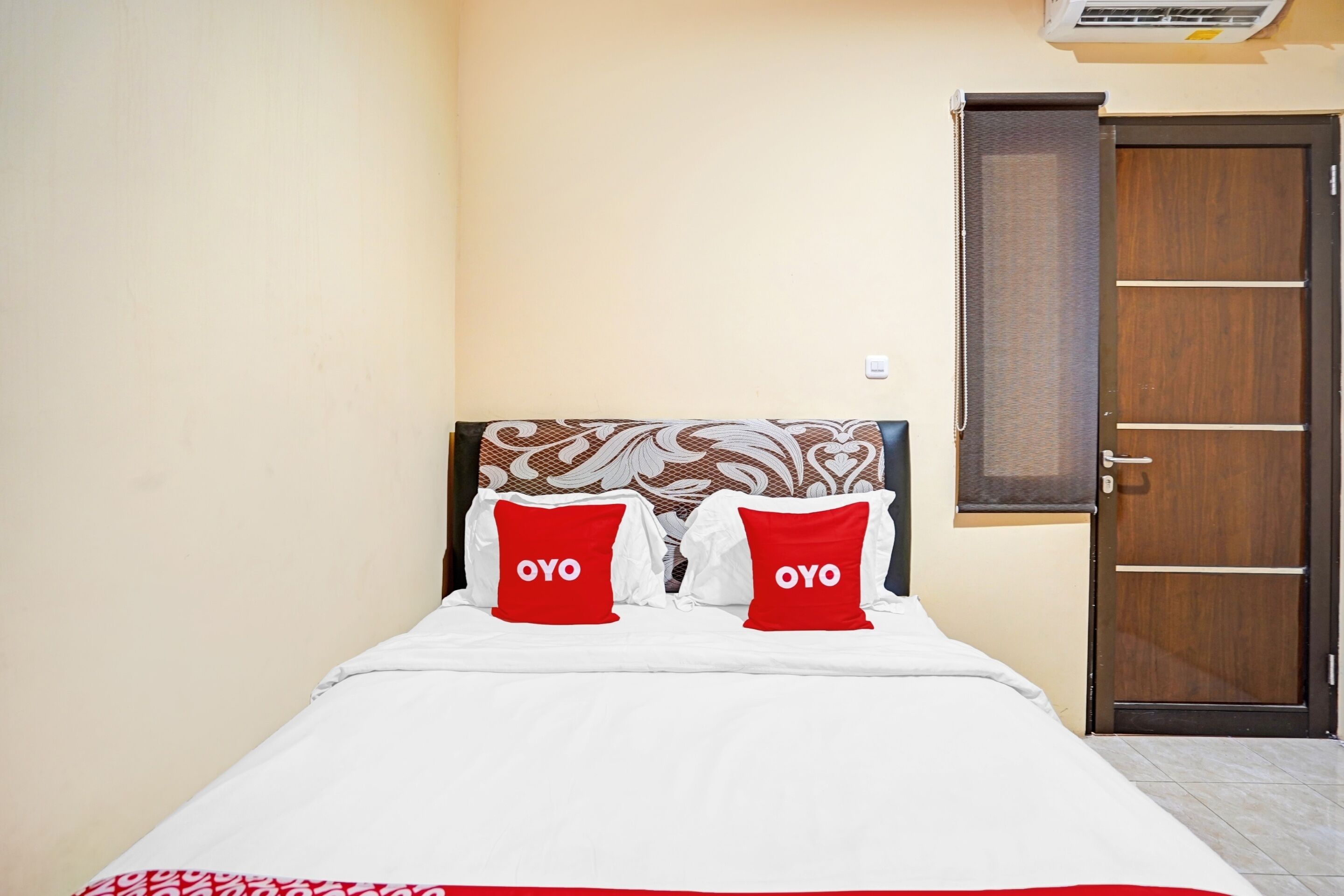 Una cama con ropa blanca y dos almohadas rojas con la palabra "OYO".