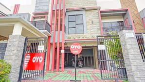 A modern residential building with a prominent red and grey color scheme, a gated entrance, and a sign indicating it is a residence.