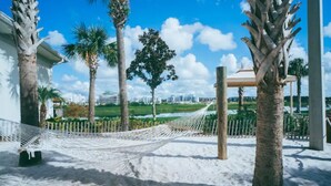 A hammock in a sandy area with palm trees and a white fence. - Disney 4 miles *Lazy River Club* Private Pool*4B/3B (Kissimmee)