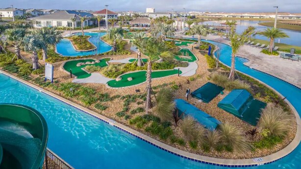 A pool area with a water slide, multiple pools, and a mini-golf course surrounded by palm trees and lounge chairs. - Disney 4 miles *Lazy River Club* Private Pool*4B/3B (Kissimmee)