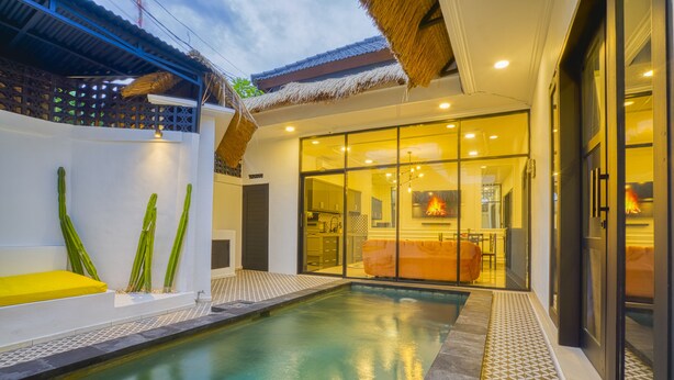 A modern pool area with a clear view of the adjacent living space, including a kitchen and seating area. - Villa Canberra (Seminyak)