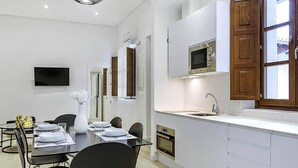 Een moderne keuken met witte kasten, een inbouwmagnetron en een roestvrijstalen spoelbak.