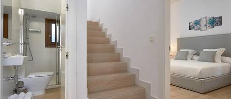 Une chambre à coucher moderne avec un lit, un escalier et une salle de bain équipée d’une douche et de toilettes.