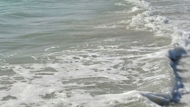 Una playa con olas y gente a lo lejos.
