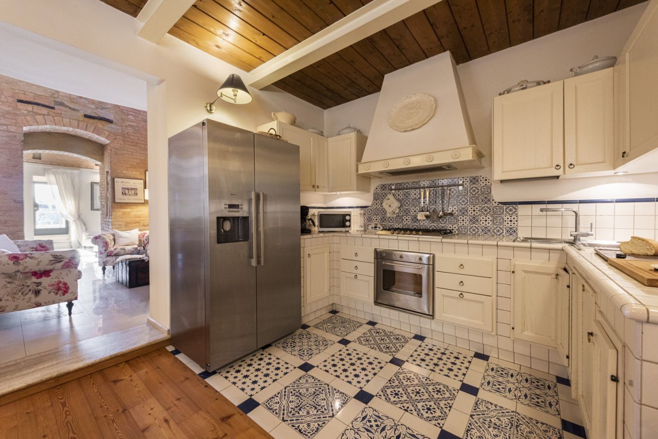 Una cucina con frigorifero in acciaio inossidabile, forno a microonde e zoccolo di piastrelle.