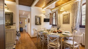 Un comedor con techo de madera, sillas blancas y una mesa dispuesta para cuatro.