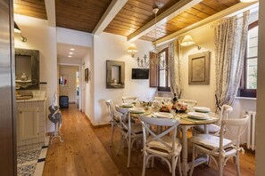 Un comedor con techo de madera, sillas blancas y una mesa dispuesta para cuatro.