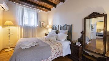 A bedroom with a bed, bedside lamps, a mirror, and a wooden floor.