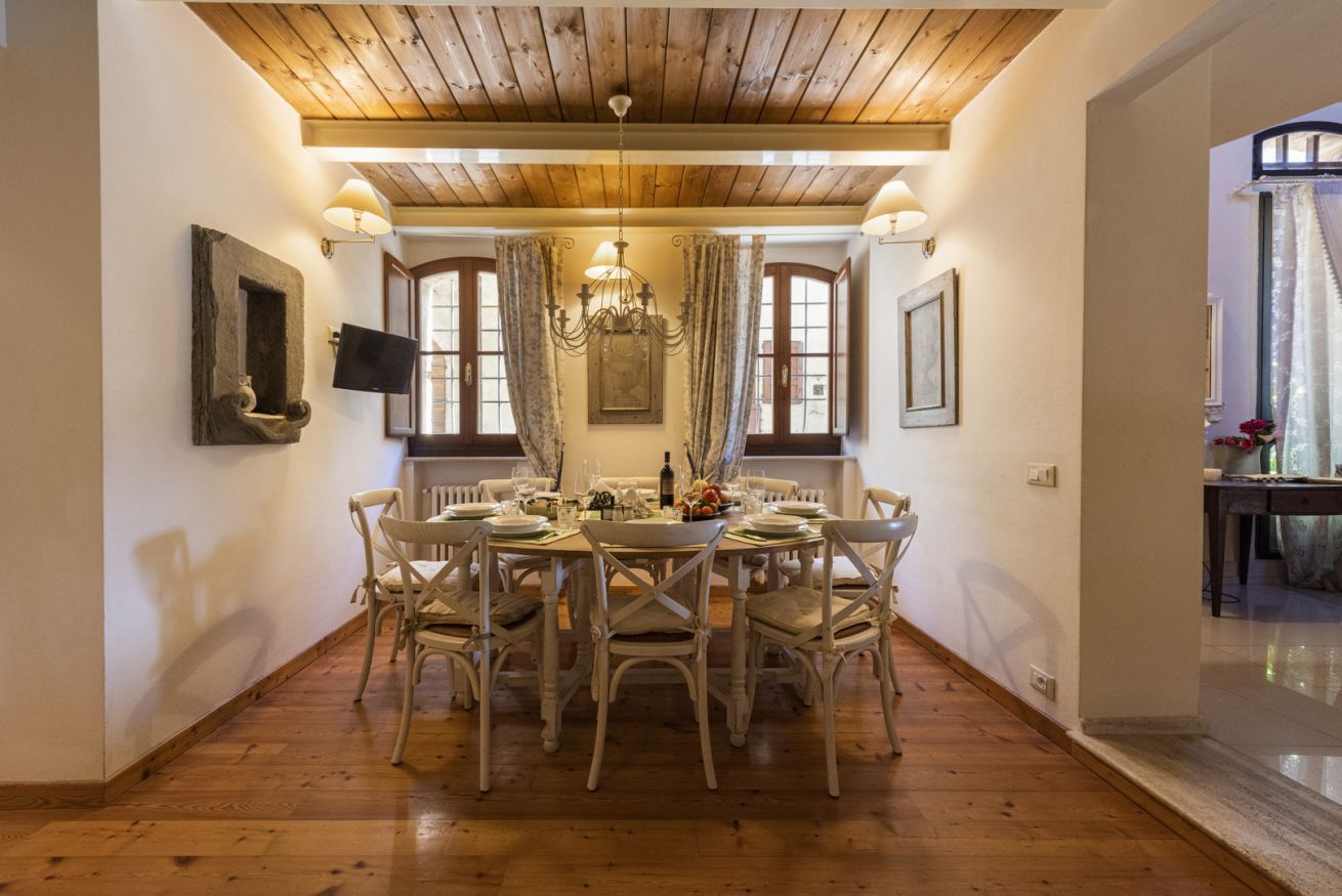 A dining area with a wooden ceiling, white walls, and a chandelier.