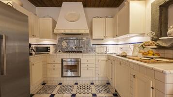 A kitchen with white cabinets, a stainless steel refrigerator, a microwave, a stove, and a tiled backsplash.