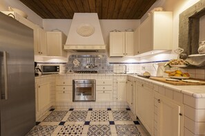 Una cocina con armarios blancos, un refrigerador de acero inoxidable, un microondas, una estufa y un salpicadero de azulejos.