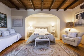 Un dormitorio con cama, una banca, una silla y un tapete decorativo.