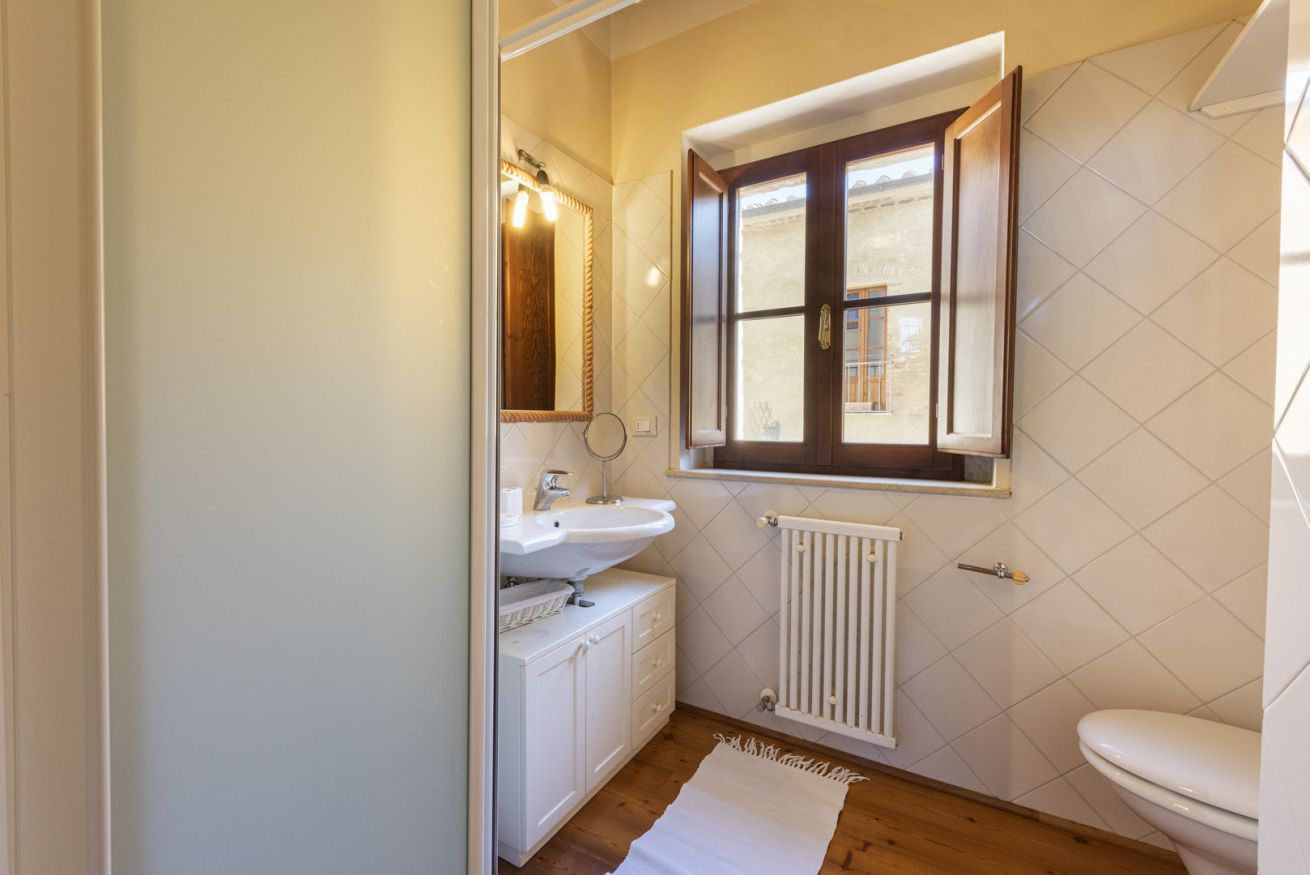 A bathroom with a white sink, mirror, and window.