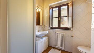 A bathroom with a white sink, mirror, and window.