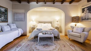 Un dormitorio con cama, una banca, una silla y un tapete decorativo.