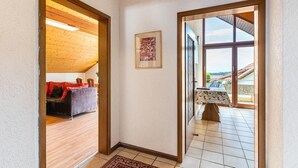 Ein Zimmer mit Holzboden, einem Sofa mit roter Decke, einem gerahmten Bild an der Wand und einem Tisch mit Tischdecke.
