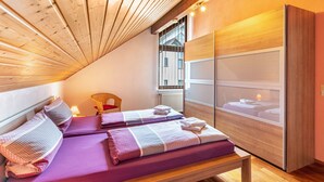 Ein Zimmer mit zwei Betten, Holzboden, einem Fenster mit Aussicht und einem Holzschrank.
