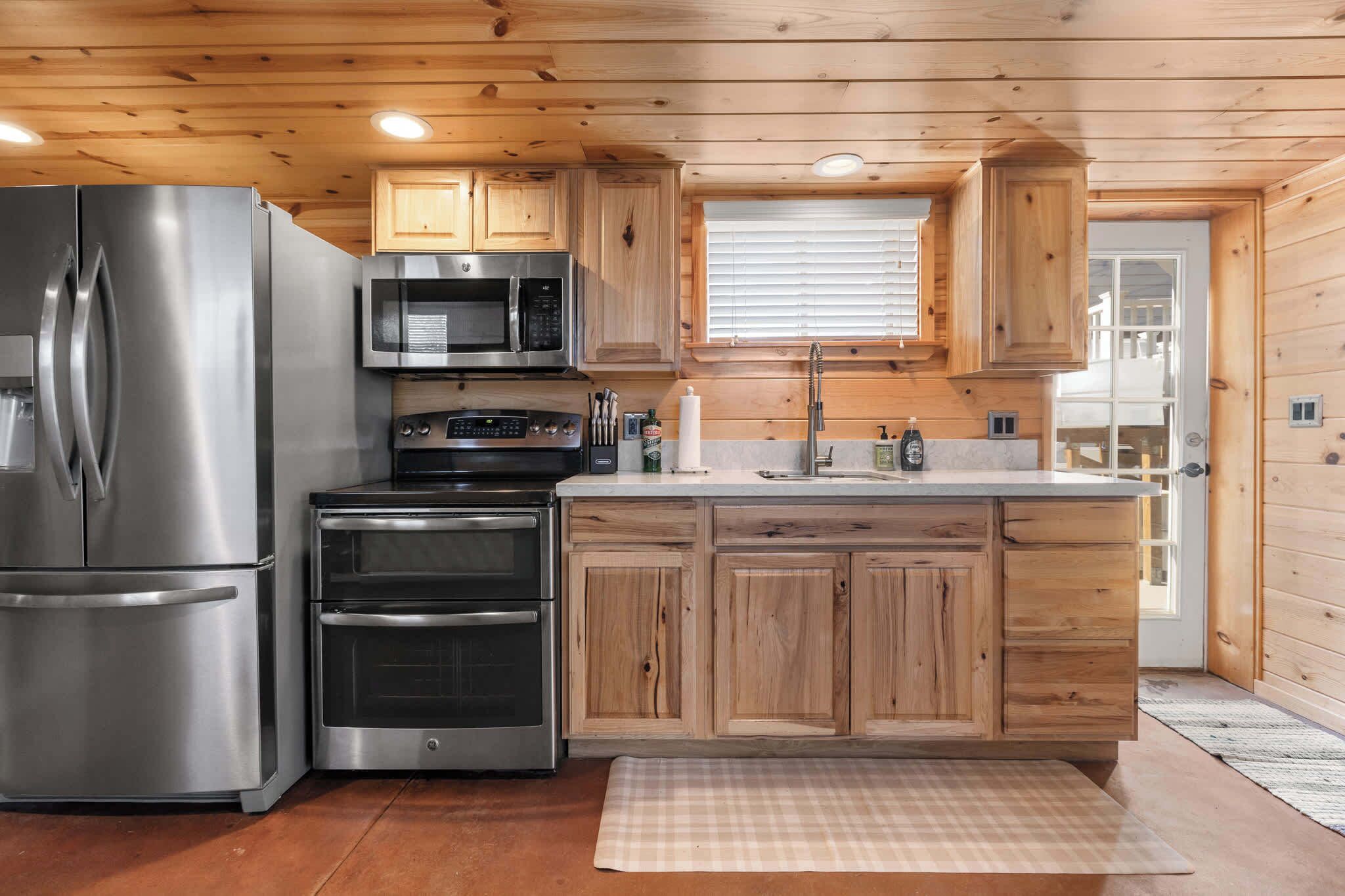 A modern kitchen with stainless steel appliances, wooden cabinets, and a central island.
