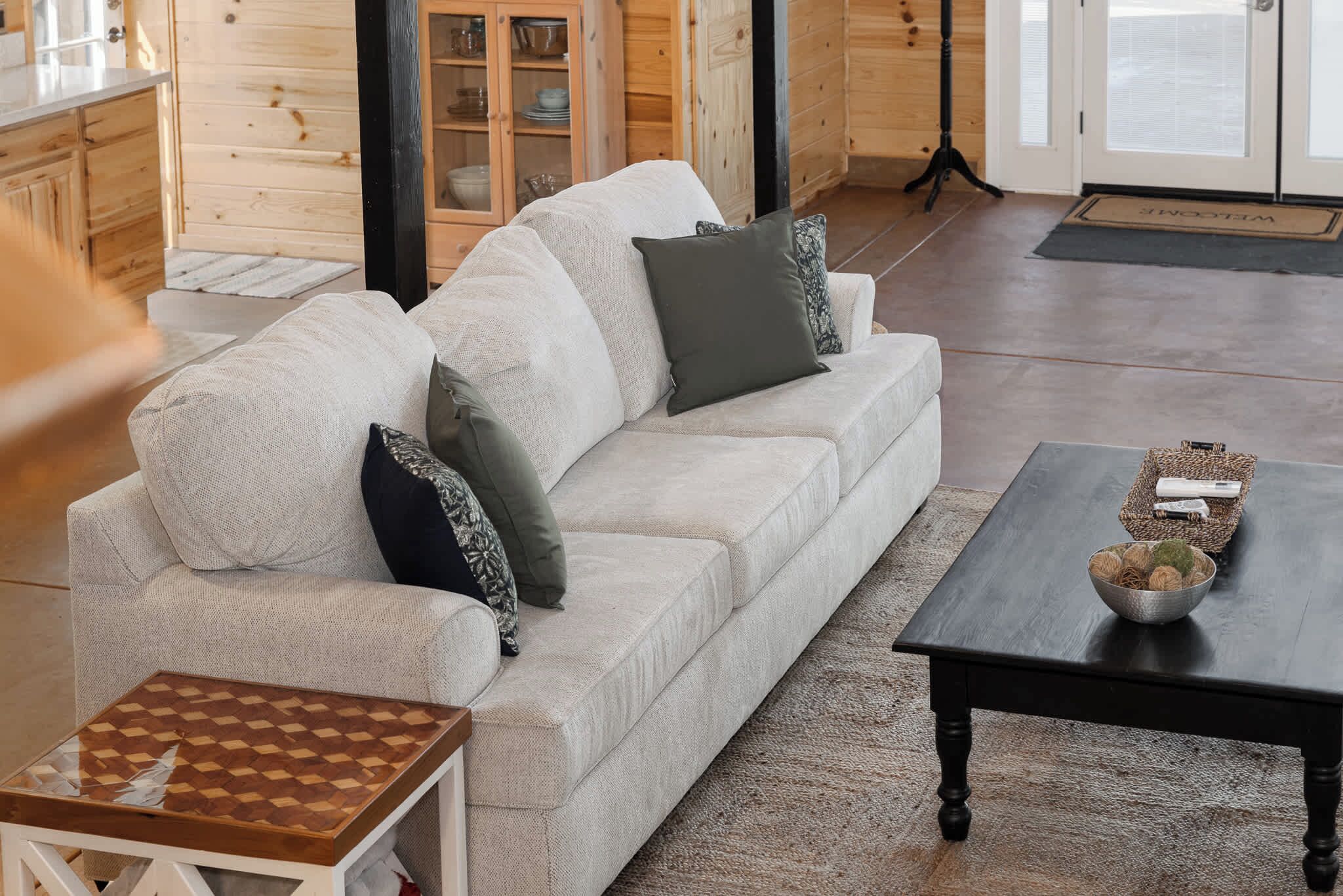 Ein gemütliches Wohnzimmer mit einem hellen Sofa, einem kleinen Holztisch und einem schwarzen Tisch.